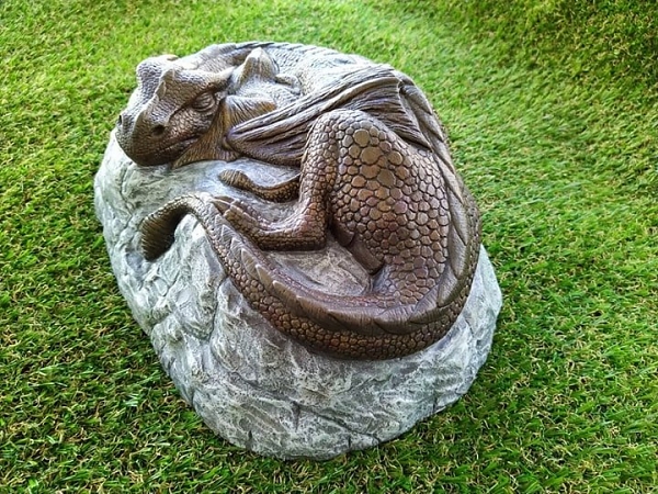 Dragon and her baby sleeping on a rock tail view of garden ornament